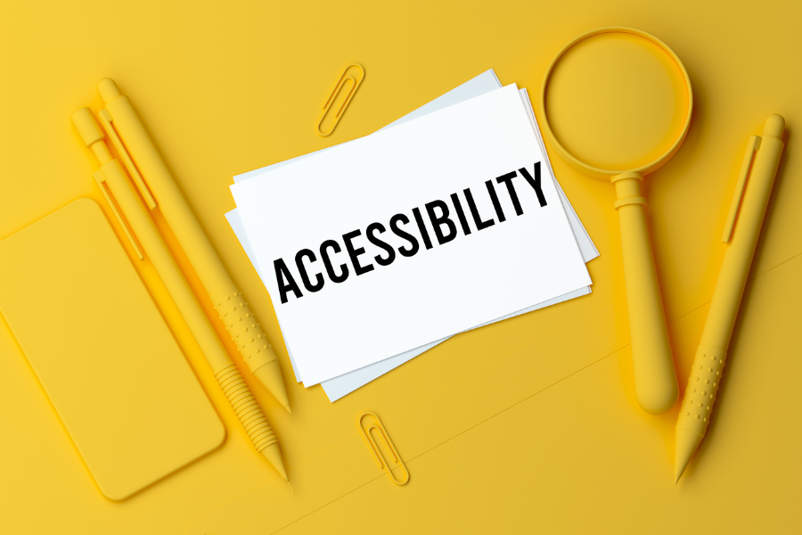 yellow backround of stationary and a mobile device with the word accessibility wriiten on paper in the middle